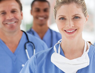 Pflegekräfte in Arbeitskleidung lächeln in Kamera