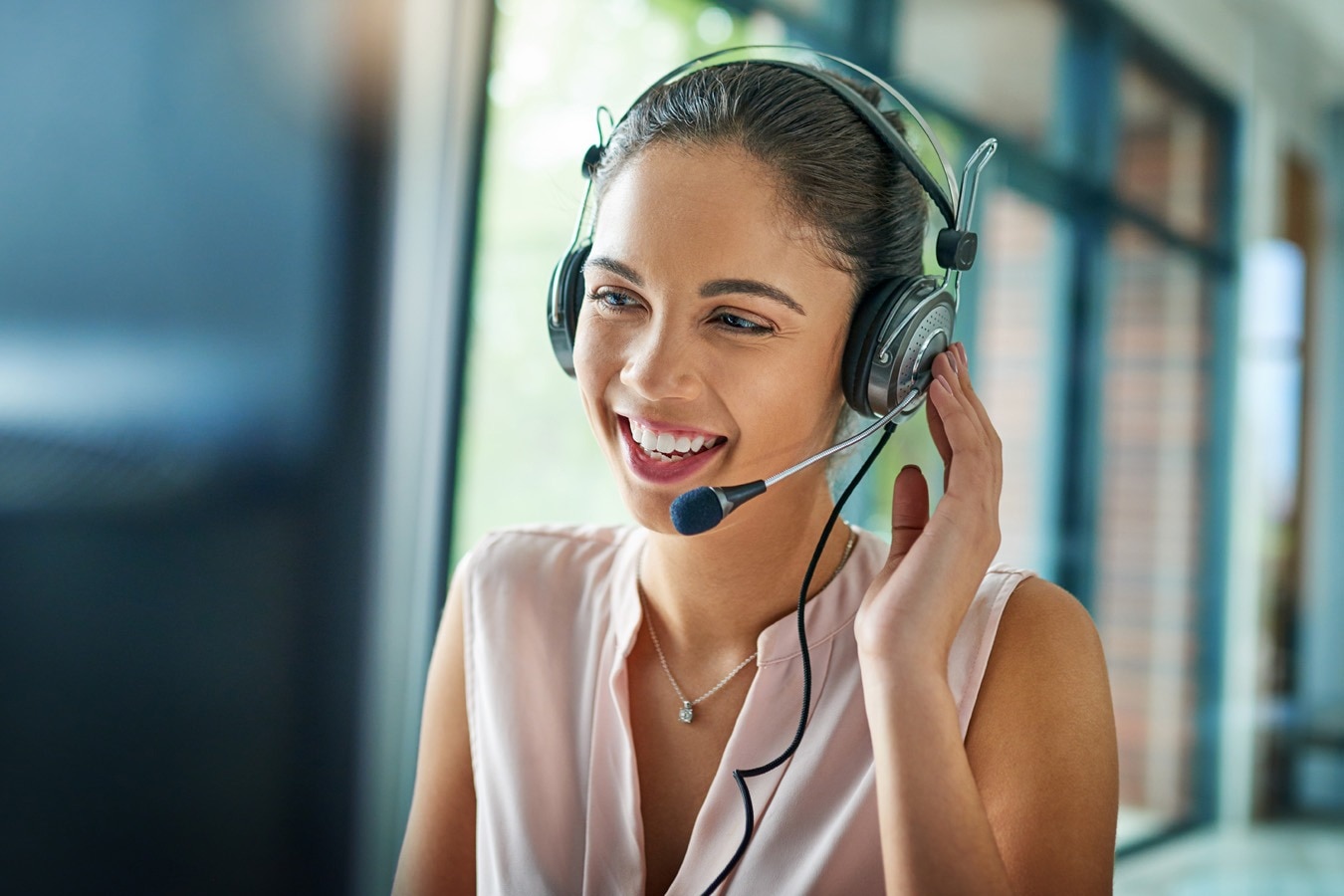 Frau mit Headset lächelt und berät telefonisch.
