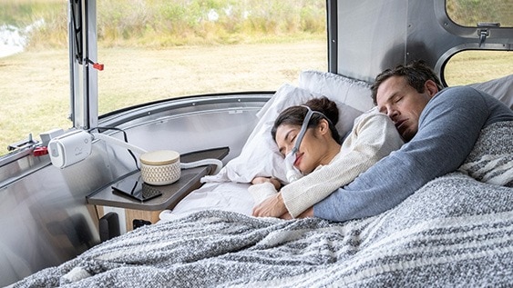 Paar schläft im Camper, CPAP-Maske und Air Mini Gerät sichtbar.