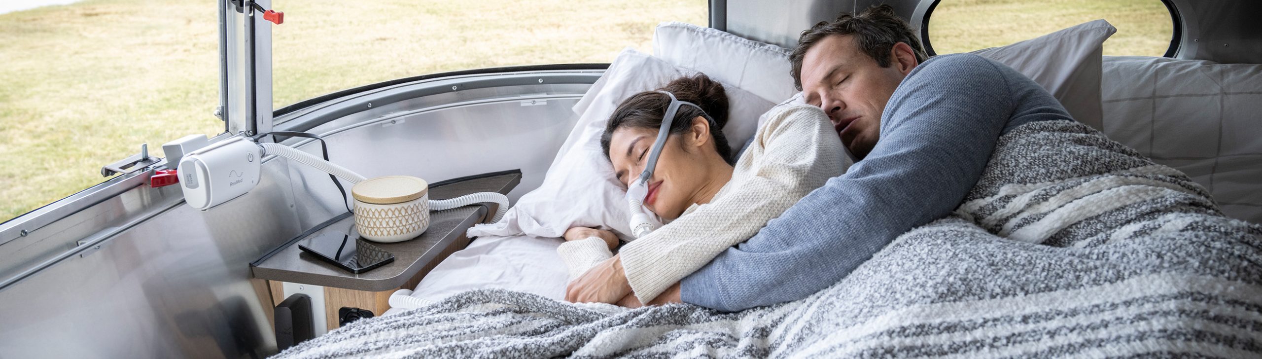Paar schläft im Camper, CPAP-Maske und Air Mini Gerät sichtbar.