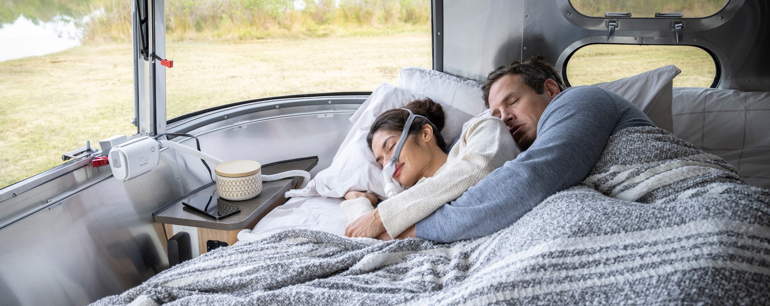 Paar schläft im Camper, CPAP-Maske und Air Mini Gerät sichtbar.