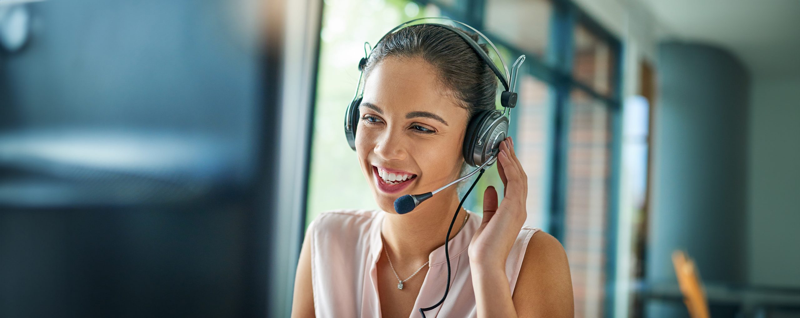 Frau mit Headset lächelt und berät telefonisch.