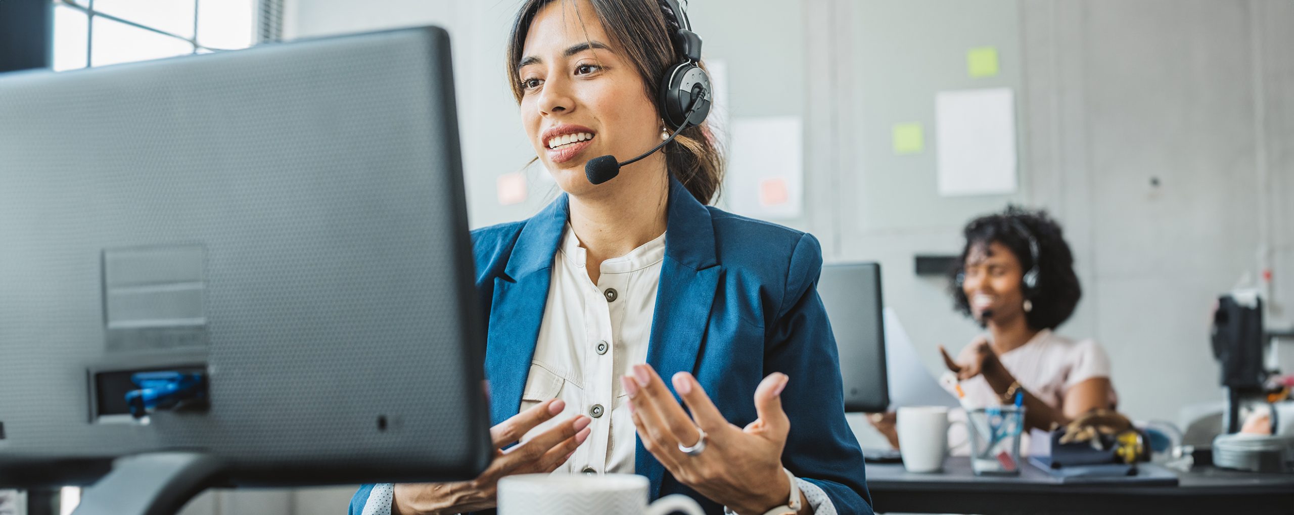 Frau mit Headset lächelt und berät telefonisch.