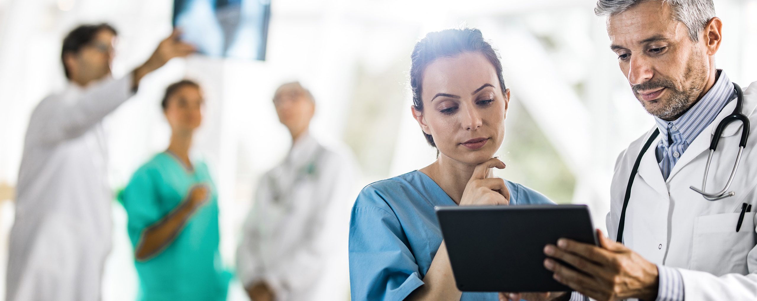 Ärztliches Fachpersonal überprüft Patientendaten auf einem Tablet.