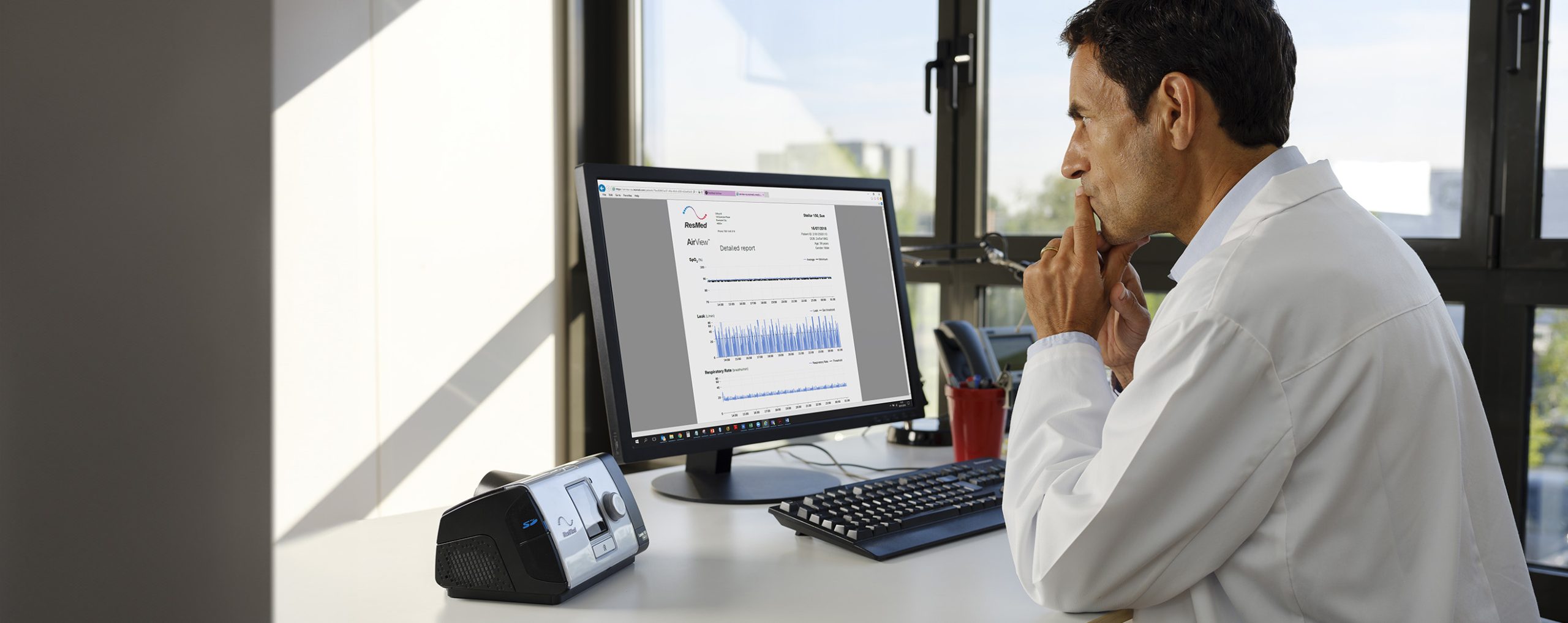 Arzt analysiert Daten eines Schlafapnoegeräts auf einem Computerbildschirm.