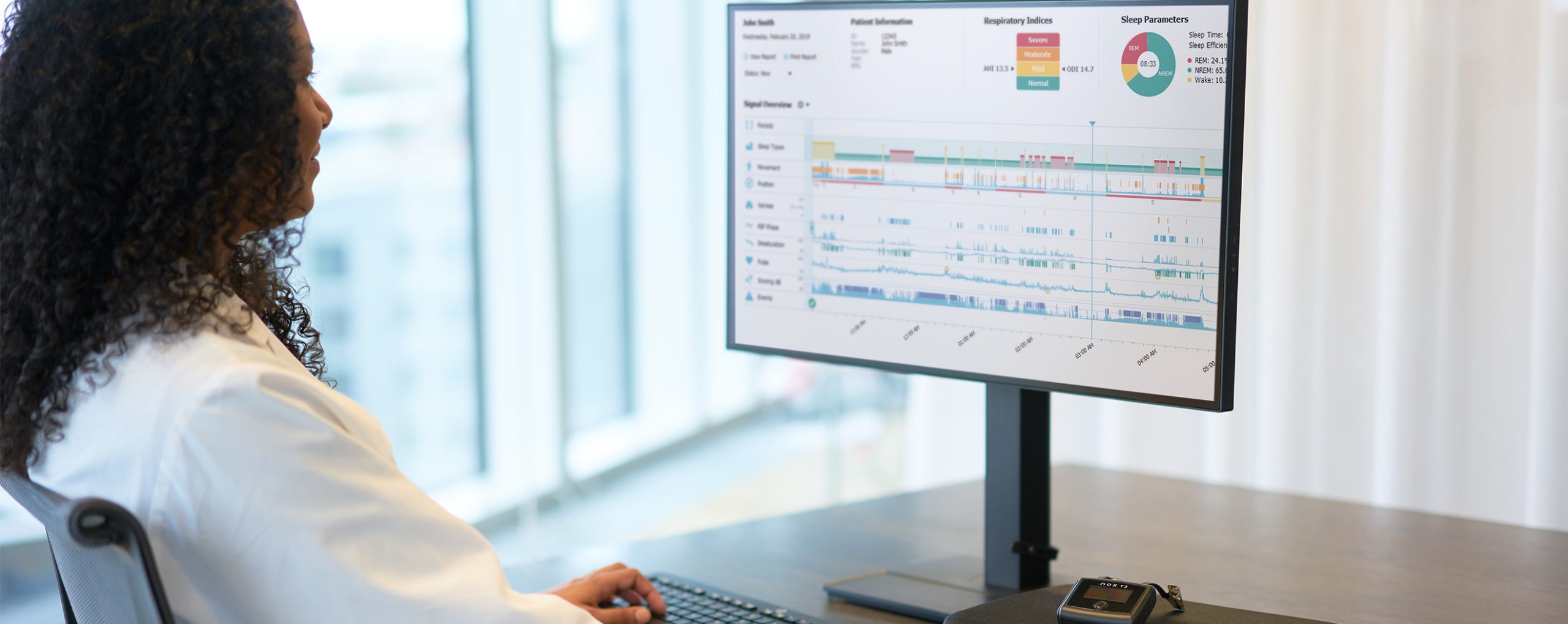 Ärztin analysiert Schlafdaten eines Patienten auf einem Monitor.